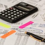 Documents financiers annotés, calculatrice et stylos sur une table