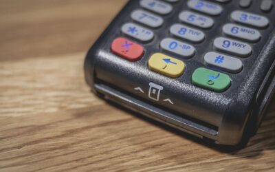 Un terminal de paiement noir avec clavier coloré sur bois